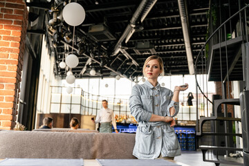 A girl running a cafe with a mobile phone, formally dressed, looks at the camera