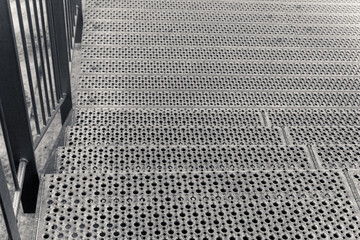 Steps covered in textured metal lead down to an inviting urban landscape at dusk