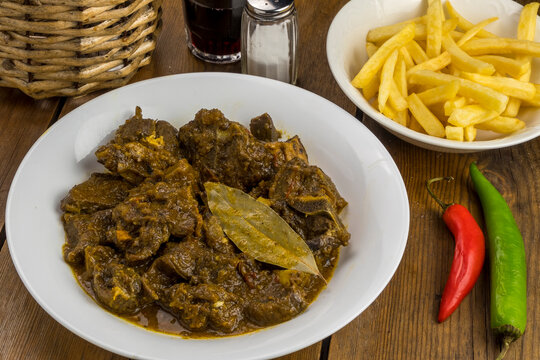 Plato con carne de cabra guisada al estilo de las islas Canarias, patatas fritas y vino tinto