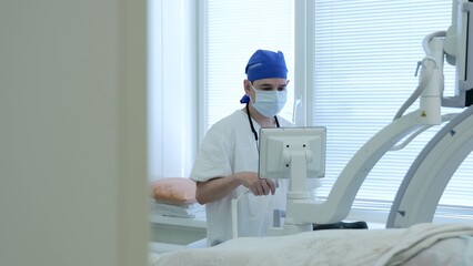 Russia Tomsk 05.07.2025: Biomedical technician calibrating surgical display equipment, scrubbed...