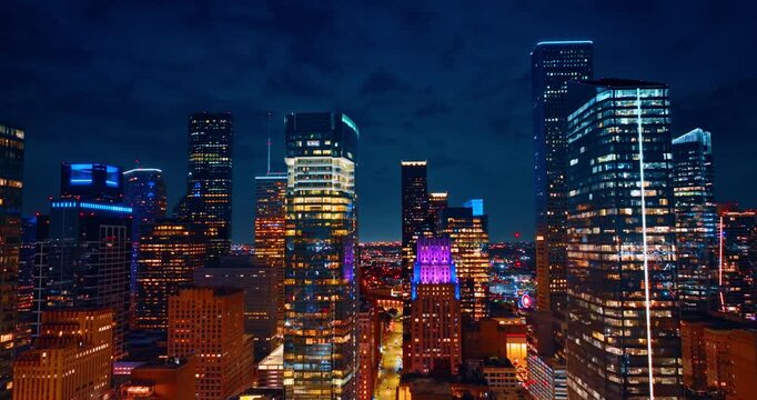 Rising to the top of the high-rise building in the downtown Houston, Texas, USA. Cloudy night sky at backdrop.