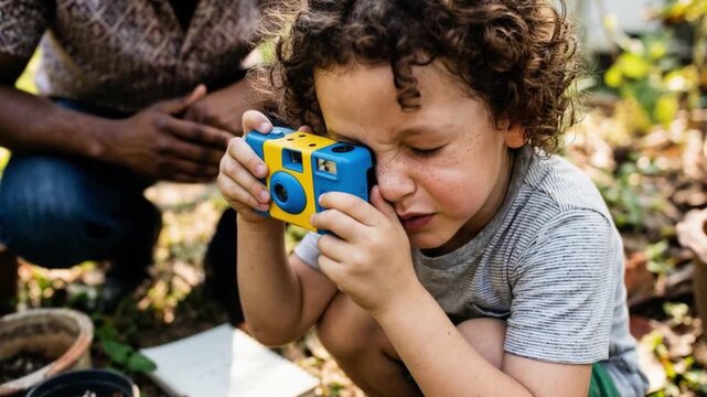 Interracial child learning photography with simple camera, curiosity creativity and self expression