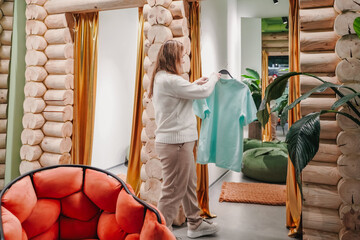 Hanging shirt on display in clothing store, shopper evaluates style before purchase. Organizing apparel in fashion boutique supports retail merchandising, shopping decision, wardrobe planning indoors.