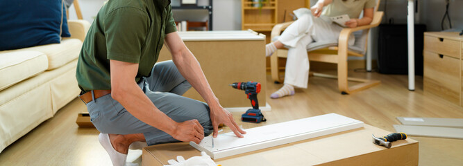 Funny and Confused Couple Assemble Furniture as a Team, Girl tries to Read Instructions and Boy Figures out how to work with Drill. Couple Having Difficulties Assembling Shelf.