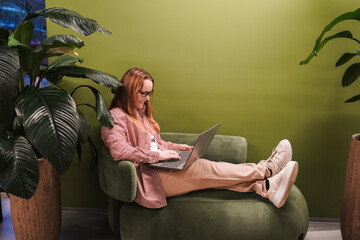 Workspace setup in store lounge, woman uses laptop for remote job tasks. Freelance writing, email, online research. Digital workday, internet connection, productivity, business management, ecommerce.