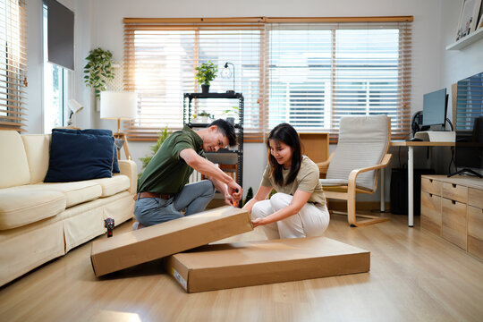 Unpacking, couple and people with boxes, moving in and bonding in new house, mortgage or investment. Relocation, asian man and woman with cardboard in living room, real estate and unboxing in home