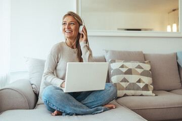 Woman Relaxing On Couch With Laptop And Headphones, Enjoying Music While Working