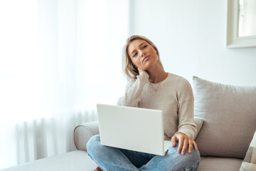 Fototapeta premium Relaxed Woman Working on Laptop at Home Couch in Natural Light, Casual Cozy Scene Today