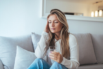 Relaxed Woman Sits on Sofa with Glass of Water, Quiet Moment of Stress and Reflection