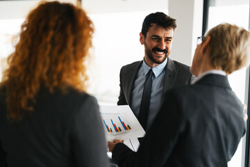Group of diverse business professionals discussing financial charts and graphs on paper during a strategy meeting in the office