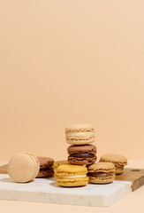 Multicolored almond macarons on a wooden board, beige background