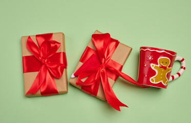 Gift box wrapped in craft paper and tied with a large bright red satin bow on a green background