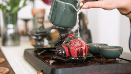 Pomegranate tea figurine. Chinese ceremony. Table with tea-board woman hand pouring water vapor steam incense service changing color.