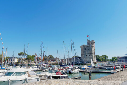 La Rochelle in Charente-Maritime - Saint Nicolas Tower, a majestic monument of medieval architecture at the entrance to the 'Vieux Port'  with the Gabut Lighthouse in the background
