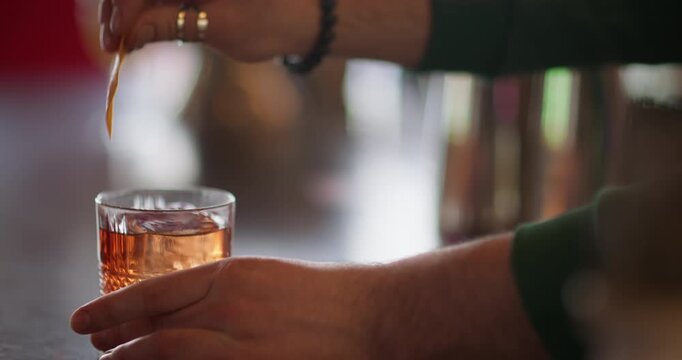 Bartender work. Refreshing alcohol. Tropical aperitif orange drink in wide glass. Hands sprinkling aromatic juice serving cocktail.