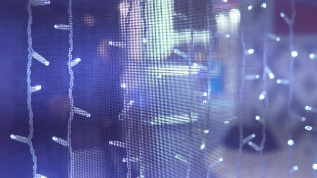 blue string lights on glass window, soft bokeh from blurred city street beyond, cool blue tones, twinkling leds, rainy reflections, faint storefront silhouettes, slow camera pan, cozy