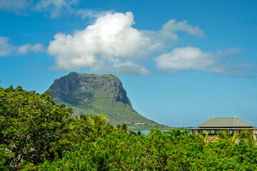Green tropical mountain Le Morne rising above lagoon with blue sky and clouds creating scenic island landscape for travel