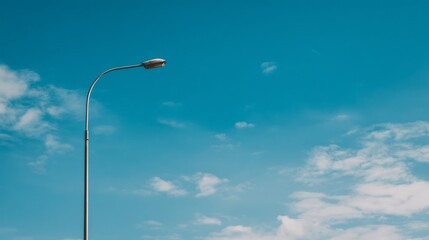 Streetlight against a clear blue sky with scattered clouds showcasing urban infrastructure and serene natural scenery in daylight