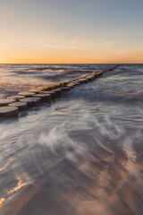 Buhnen in Wustrow an der Ostsee bei Sonnenuntergang mit Wellen in der Langzeitbelichtung
