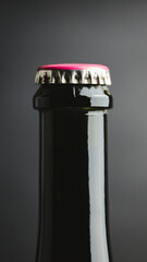 Macro of glass bottle neck with pink crown cap on dark background