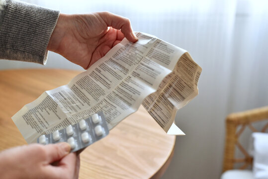 Woman holding patient information leaflet and blister with pills