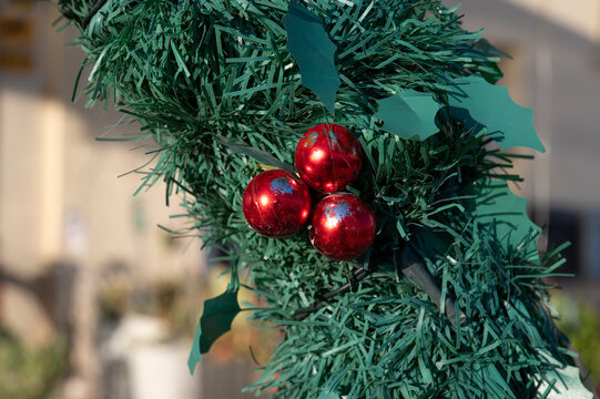 Kitsch but visually striking Christmas decoration with artificial green pine needles and red baubles as background detail in Birzebbuga Birzebbuga, Malta, 6 DEC 2025.