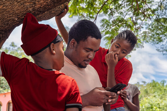 social worker volunteer from a NGO charity, teaching kids wireless technology on a phone in a remote village in Africa