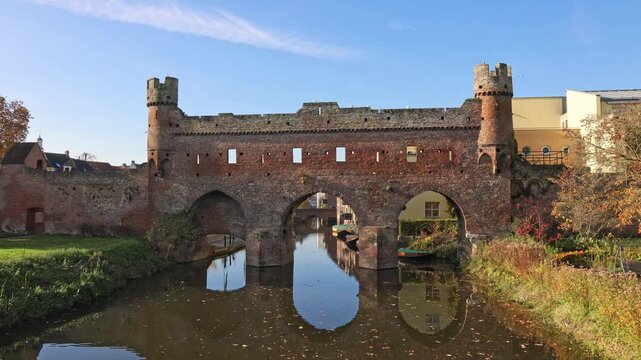 Medieval Berkelpoort water gate in Zutphen, Netherlands. Historic brick fortification spanning the river with clear reflections on a sunny day.