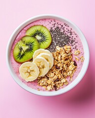 Smoothie bowl with fruits, granola, and seeds served on a pink background in a bright setting during daytime