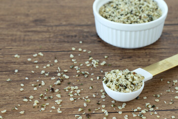 Organic hemp seeds in a spoon on wooden table. Copy space.