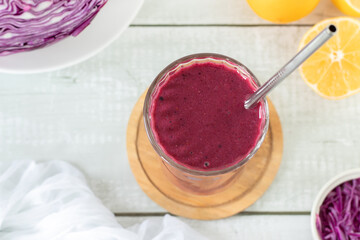 Red cabbage smoothie in a glass on white wooden table. Top view. Healthy homemade blended drink.