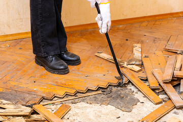 A woman is dismantling the old parquet on the floor.