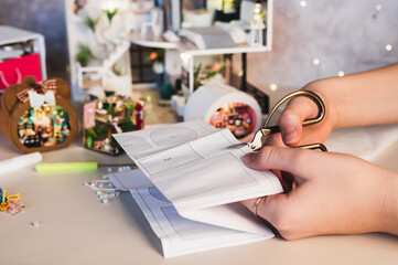 A girl cuts out a paper piece for a roombox pattern