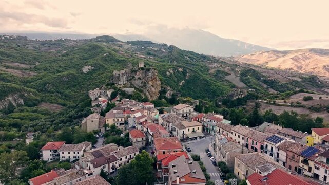 Roccascalegna castle on a rock, aerial panorama of medieval town, mountains and farmlands at sunset light.