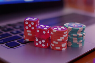 Laptop keyboard with red dice and poker chips symbolizes the idea of online betting and gambling