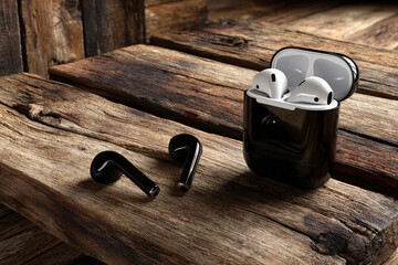 Wireless earbuds on rustic wooden table with open case showing earphones