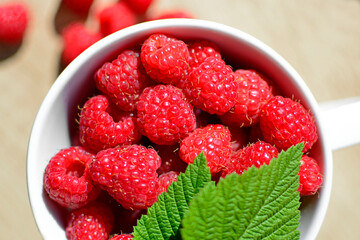 maliny w białym kubku, czerwone maliny, maliny z zielonym listkiem, fresh raspberries in a cup, red raspberries, juicy raspberries with a green leaf, Rubus idaeus, rasberry view from above,białe tło