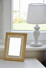 drewniana ramka na zdjęcie stojąca na białym stole, wooden photo frame on the white table, Frame with empty space for picture, Portrait wooden frame standing against window on white table