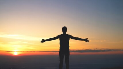 Fototapeta premium Silhouette of person with arms outstretched at sunset over a mountain landscape