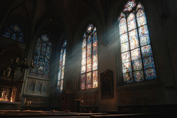 Obraz premium Interior of a historic church featuring stunning stained glass windows, sunlight streaming through, illuminating wooden pews, creating a serene and spiritual atmosphere for reflection and worship