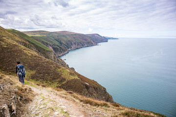 Hiker walking along the South West Coast Path above the sea in Exmoor National Park, Devon, England