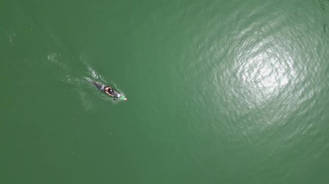 Top-down view of a person paddling in a canoe. A boy is playing sports outdoors in the nature on a summer day
