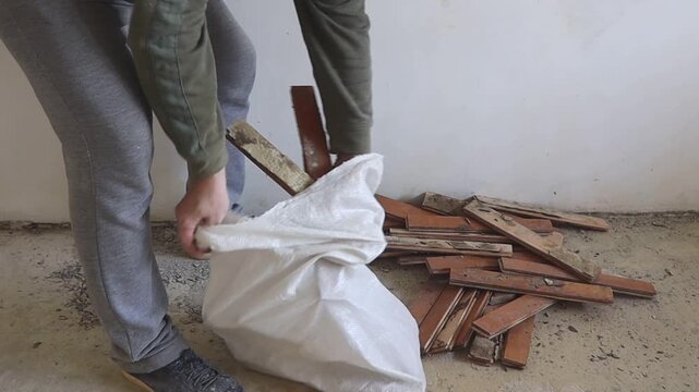 A worker packs old dismantled parquet into bags.