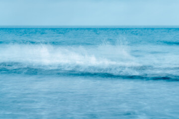 Fototapeta premium Ocean scene with a single breaking wave rendered in cool blue motion.