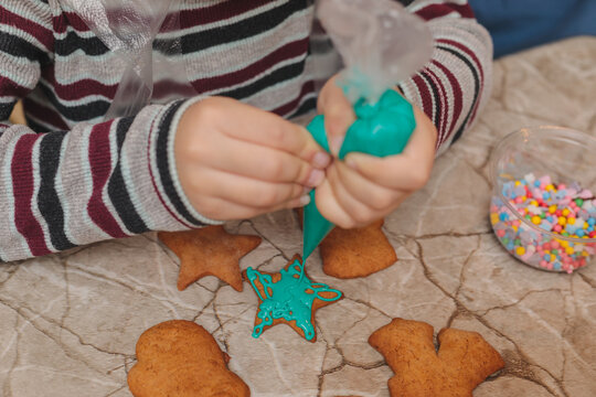 Close up of child hands decorating star shaped gingerbread cookie with turquoise icing and colorful sprinkles, creative Christmas baking and festive holiday culinary workshop for kids at home - Powered by Adobe