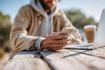 A man is sitting at a table with a laptop and a cell phone