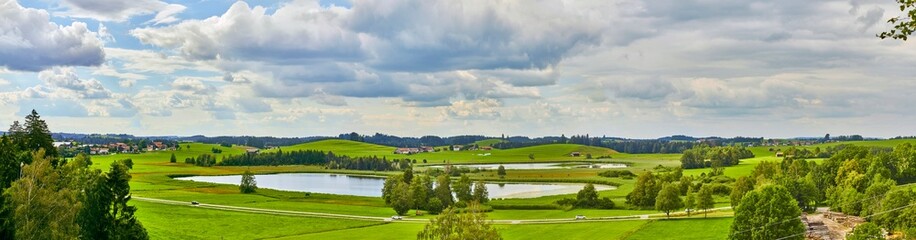 Obraz premium Grosses Panorama in der Nähe der Ortschaft “Seeg im Allgäu“ mit einem Teich im Vordergrund.