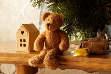 A New Year's still life with a child's teddy bear, a Christmas tree, a candle, and a gift on a wooden table at home