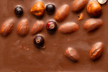 Milk chocolate bar with almonds, hazelnuts, and whole berries, sweet dessert texture and natural ingredients
