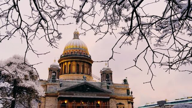 St. Petersburg, Russia - November 23, 2025: View of the snow-covered St. Isaac's Square with snow-covered trees and St. Isaac's Cathedral on a winter day at sunset. 4K